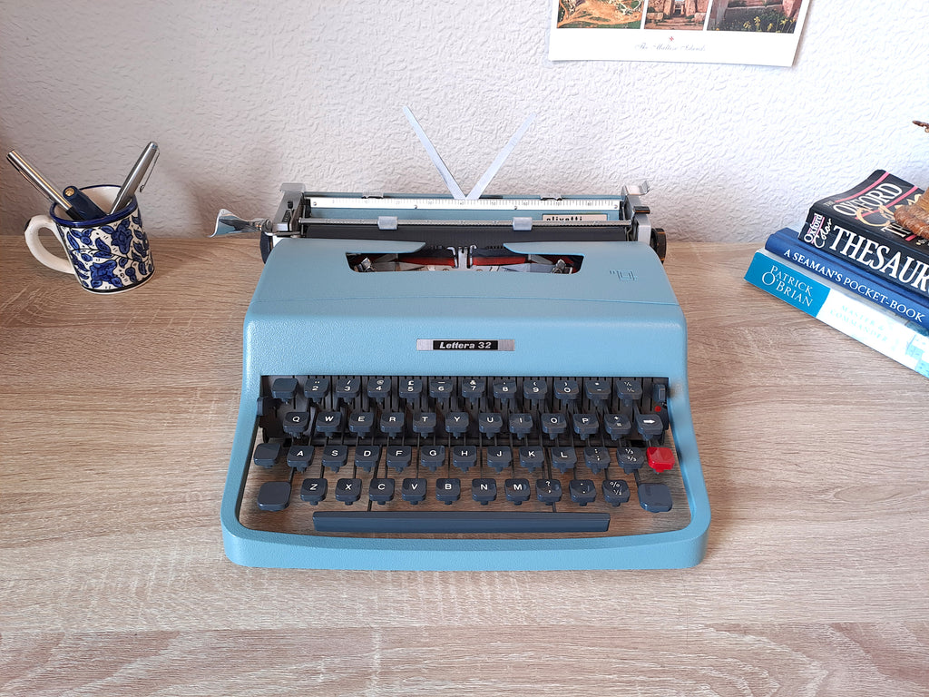 A blue vintage Olivetti Lettera 32 typewriter, front view