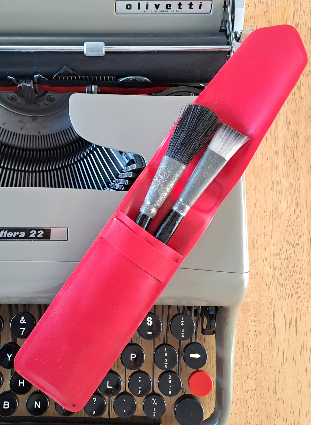 Original Olivetti brushes in a red pouch, resting on a Lettera 22 typewriter